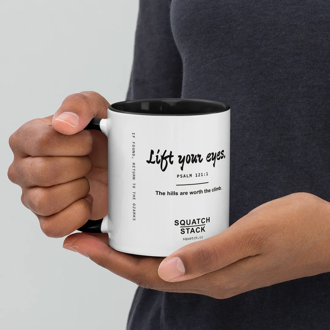 The Lift Your Eyes mug, held by the handle.